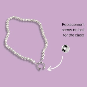 May include: A white pearl necklace with a silver clasp. The clasp is a horseshoe shape with a small ball on each end. A replacement screw-on ball for the clasp is shown separately.