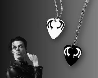 May include: Two silver chains with black and white guitar pick pendants. The picks have a stylized design with a black outline and a white interior.