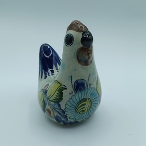 Könnte beinhalten: Eine handbemalte Keramik-Vogelfigur mit blauen, grünen, gelben und weißen Blumendesigns. Der Vogel hat einen braunen Schnabel und schwarze Augen.