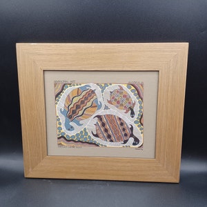 May include: A framed print of Aboriginal art depicting three turtles with intricate patterns in shades of brown, yellow, blue, and white. The print is titled "Turtles Laying Eggs" and is labeled "Aboriginal Art" and "Australia".