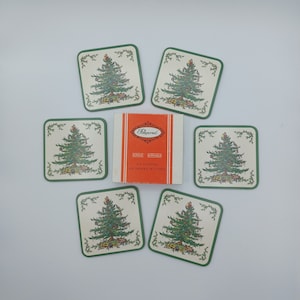 Op de afbeelding: Set van zes groene en witte kerstboomonderzetters met een groene rand. De onderzetters zijn gemaakt van acryl en hebben een feestelijk ontwerp. De doos heeft de tekst "Pepperell Acryl Zes Onderzetters Zes Dessous de Verres".