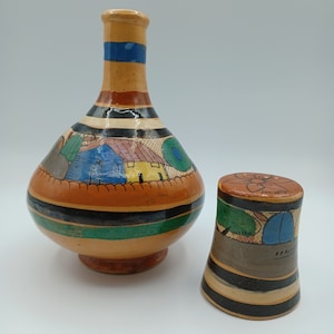 May include: A set of two hand-painted ceramic pottery pieces. The larger piece is a bottle with a wide base and a narrow neck. The smaller piece is a cup. Both pieces are decorated with colorful stripes and geometric patterns.