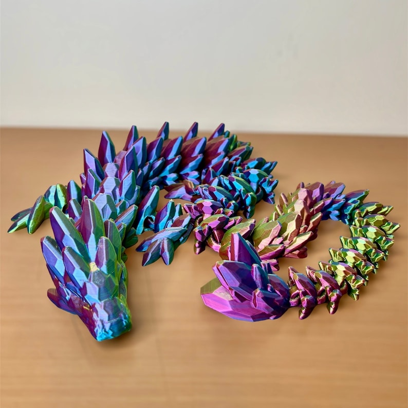 May include: A multi-colored iridescent dragon sculpture made of plastic. The dragon is made up of many small, pointed pieces that resemble scales. The dragon is curled up in a coil.
