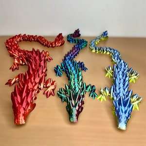 May include: Three iridescent dragon figurines, one red, one green, and one blue. Each dragon is made of a shiny, scaly material and has a long tail and a pointed snout.