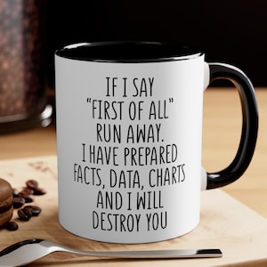 May include: White ceramic mug with a black interior and handle. The mug features the text "IF I SAY 'FIRST OF ALL' RUN AWAY. I HAVE PREPARED FACTS, DATA, CHARTS AND I WILL DESTROY YOU" in black, bold font.