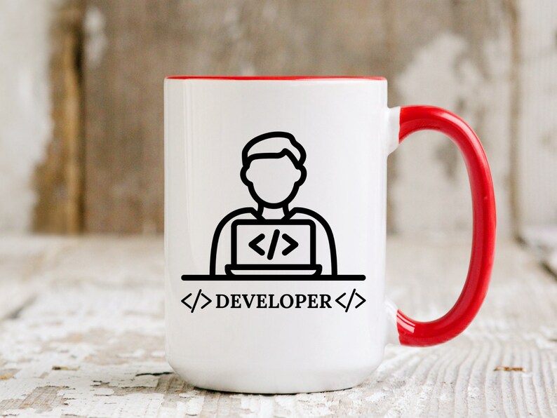 May include: White ceramic mug with a red interior and handle. The mug features a black line drawing of a person working on a laptop, with the word "DEVELOPER" below. The design is simple and modern, suitable for a tech professional.