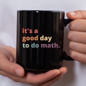 May include: Black coffee mug with a rainbow colored text that reads "it's a good day to do math."