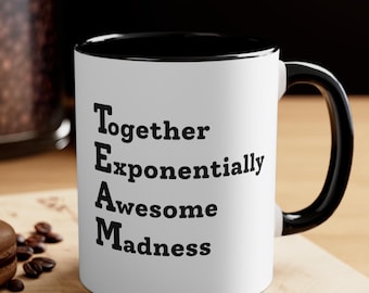 May include: White ceramic mug with a black interior and handle. The mug features the word "TEAM" in large black letters, with each letter representing a word: Together, Exponentially, Awesome, Madness.