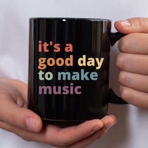 May include: Black coffee mug with the text "it's a good day to make music" in rainbow colors.