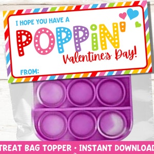 May include: A printable Valentine's Day treat bag topper with the text "I hope you have a POPPIN' Valentine's Day!" and a purple pop-it toy. The topper has a rainbow striped border.