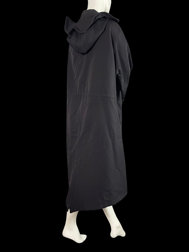 May include: A long, black hooded coat. The coat has a drawstring waist and a long, flowing skirt. The hood is large and covers the head. The coat is made of a lightweight material and appears to be suitable for layering.