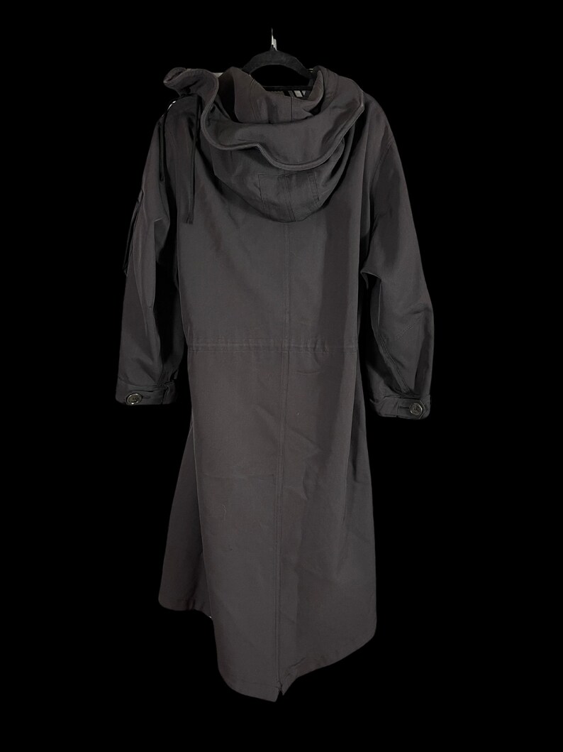 May include: A long, dark gray coat with a large hood, hanging on a black hanger. The coat has a button closure and pockets. The coat is made of a durable material.