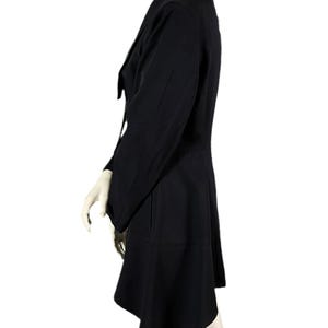 May include: A black blazer with a unique asymmetrical hemline. The blazer features a notched lapel, long sleeves, and a tailored fit. The garment is displayed on a mannequin against a white background.