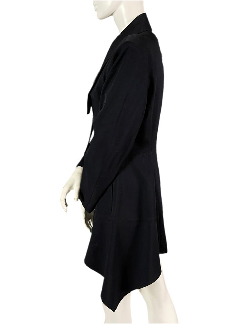 May include: A black blazer with a unique asymmetrical hemline. The blazer features a notched lapel, long sleeves, and a tailored fit. The garment is displayed on a mannequin against a white background.