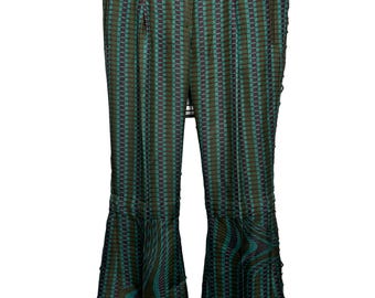 May include: Trousers featuring a dark green and dark purple checkered pattern throughout the upper section, transitioning into a wavy, distorted grid print at the flared hems. The trousers include a waistband with belt loops and a button closure.