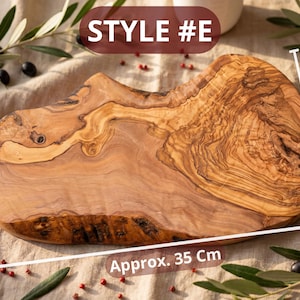 May include: A wooden cutting board, style #E, with a natural edge and a light brown color. The board is approximately 14 inches long and 8-12 inches wide. Olive branches and berries surround the board.