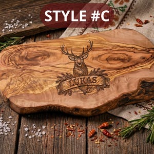 May include: A wooden cutting board with a deer engraving and the name "Lukas" on a banner. The board has a natural edge and is surrounded by rosemary, salt, and spices. The text "STYLE #C" is in the top left corner.