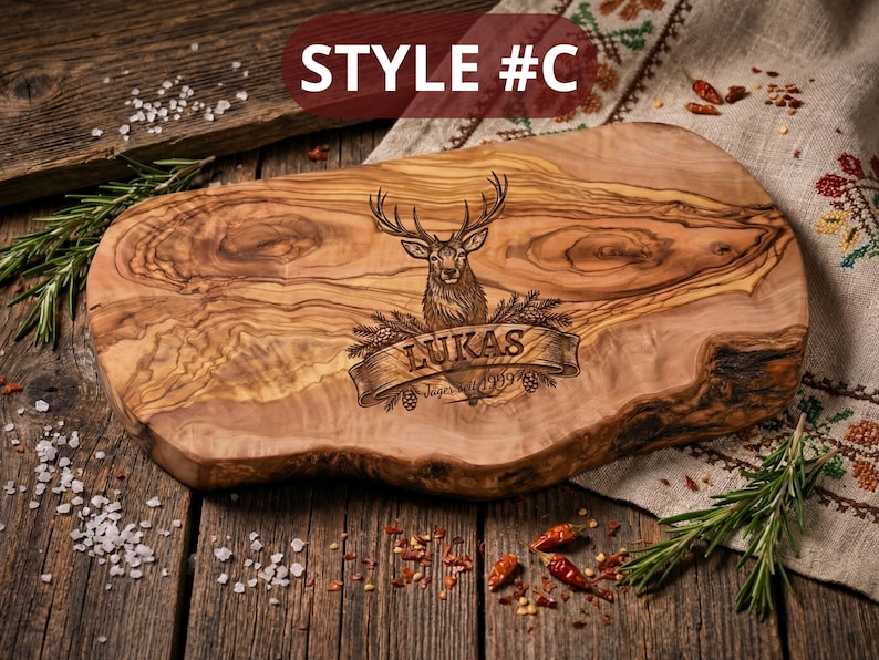 May include: A wooden cutting board with a deer engraving and the name "Lukas" on a banner. The board has a natural edge and is surrounded by rosemary, salt, and spices. The text "STYLE #C" is in the top left corner.