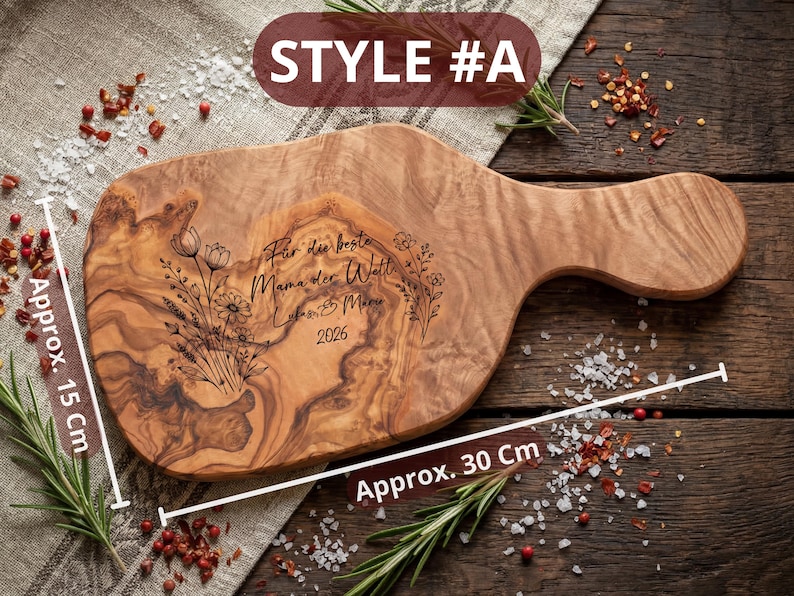May include: A wooden cutting board with a handle, measuring approximately 12 inches long and 6 inches wide. The board features engraved floral designs and text in German. The text reads "F&uuml;r die beste Mama der Welt" and "Lukas & Mia 2026".