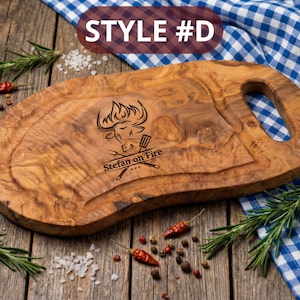 May include: Oval-shaped wooden cutting board with a handle, featuring a carved design of a bull's head and the text "Stefan on Fire." The board is surrounded by rosemary sprigs, red peppers, and salt.