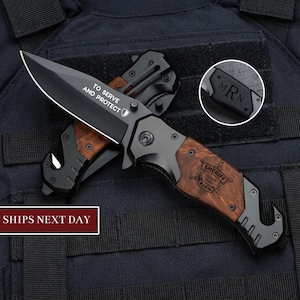 May include: A black folding knife with a wooden handle and a black blade. The blade has the text "TO SERVE AND PROTECT". The handle is engraved with "SHERIFF COOK COUNTY #3406". The knife also has a clip and a small engraving with the initials "MRN".