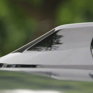 May include: A black car antenna fin, also known as a shark fin antenna, is a popular aftermarket accessory for vehicles. It is designed to improve radio reception and add a sporty look to the car.