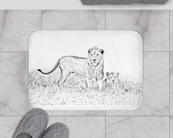 May include: A white bath mat featuring a black and white sketch of a lion and lioness in a grassy field.