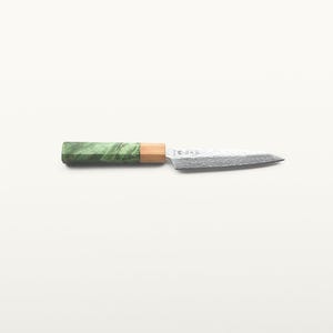 Peut inclure: Un couteau de cuisine doté d'une lame en acier pointue avec une finition texturée et des caractères japonais près de la mitre. Le manche se compose d'une section en bois brun clair reliée à un embout cylindrique en marbre vert.