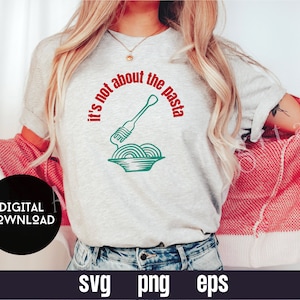 Könnte beinhalten: Ein graues T-Shirt mit dem Text "It's not about the pasta" in Rot und Grün. Der Text befindet sich in einem Kreis mit einer Gabel und einer Schüssel Pasta im Kreis.