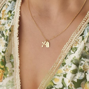 May include: A gold chain necklace with a small cross and a rectangular tag pendant.