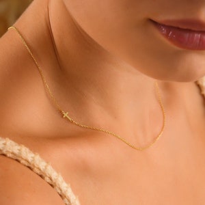 May include: A delicate gold chain necklace with a small cross pendant.