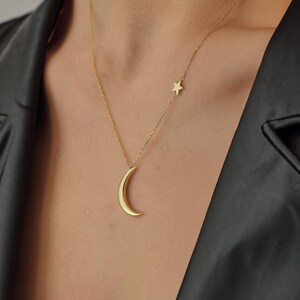 Pu&ograve; includere: Una collana d'oro con un ciondolo a forma di luna crescente e un piccolo ciondolo a forma di stella.