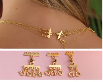 May include: Gold necklace extender with three loops and a T-bar connector. The extender has a chain with multiple small loops. The connector has a T-shaped bar with two loops on each end.
