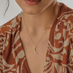 May include: A gold necklace with a crescent moon pendant and a small star charm.