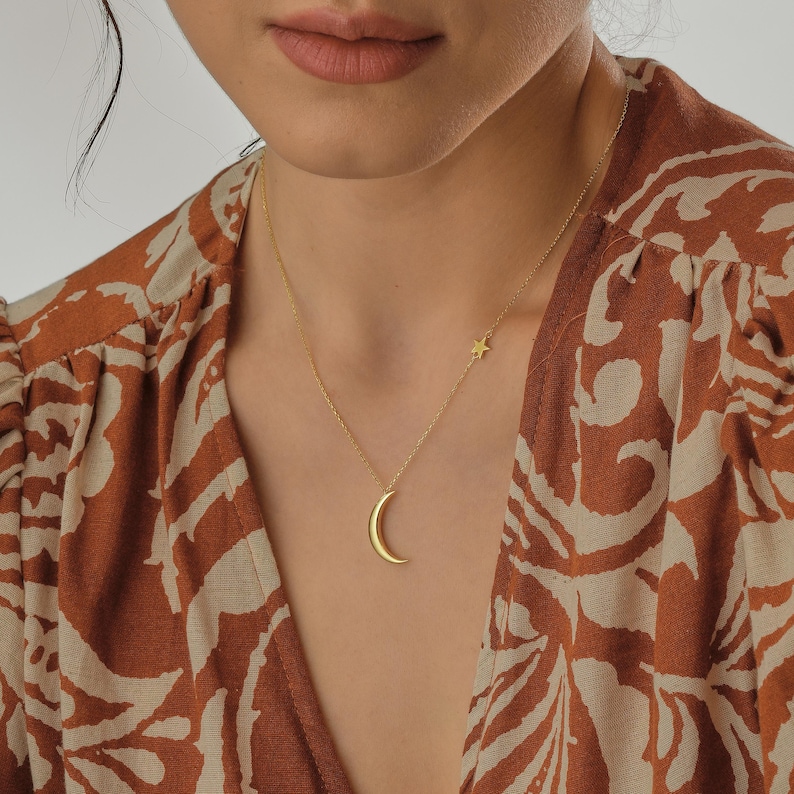 May include: A gold necklace with a crescent moon pendant and a small star charm.