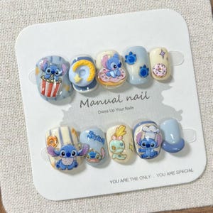 May include: A set of press-on nails featuring the character Stitch from Lilo & Stitch. The nails are painted with various designs, including Stitch with popcorn, donuts, and other themed elements. The text "Manual nail" and "Dress Up Your Nails" is visible.