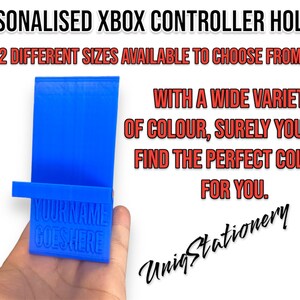May include: A blue 3D printed Xbox controller holder with the text "YOUR NAME GOES HERE" on the front. The holder is designed to stand upright and hold a controller.