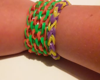 May include: A colourful rubber band bracelet with green, orange, yellow and purple bands.