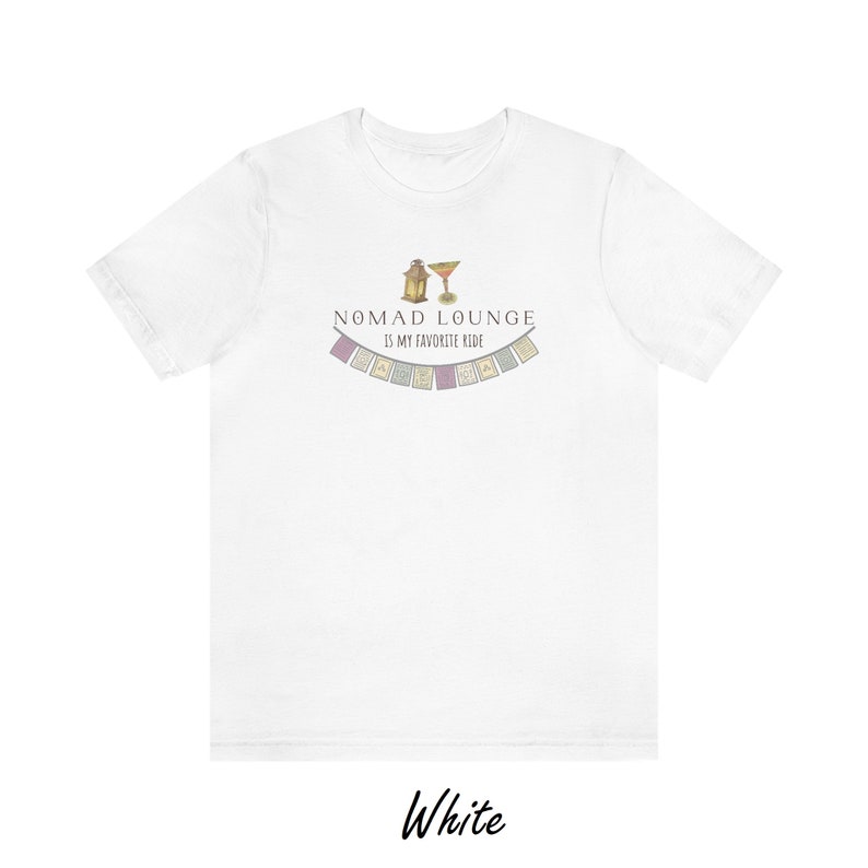 K&ouml;nnte beinhalten: Wei&szlig;es T-Shirt mit einem grafischen Design einer Laterne und eines Cocktailglases mit dem Text "Nomad Lounge is my favorite ride" und einer Reihe bunter Flaggen.