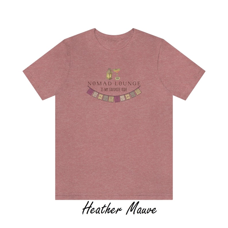 K&ouml;nnte beinhalten: Heather-mauvefarbenes T-Shirt mit einem Grafikdruck eines Cocktails und dem Text "Nomad Lounge is my favorite ride" sowie einer Girlande aus bunten Flaggen.
