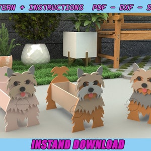 May include: Three dog-shaped planters in shades of tan, gray, and peach. The planters have a rectangular box shape for holding plants, with the dog's face and body forming the decorative exterior. The image includes the text "PATTERN + INSTRUCTIONS PDF - DXF - SWG" and "INSTAND DOWNLOAD".