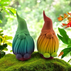 May include: Two colorful garden gnomes with rainbow-colored beards and hats. The gnomes are standing on a bed of green moss.