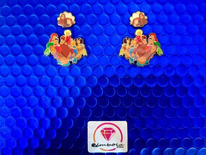May include: Enamel pins featuring cartoon characters on a blue background. The pins depict a group of characters and a smaller pin with three figures. A logo with a diamond is at the bottom.