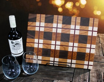 May include: A wooden cutting board with a plaid pattern in shades of brown, white, and dark wood. A bottle of wine and two stemless wine glasses are next to the board. The wine bottle has a white label with black text.