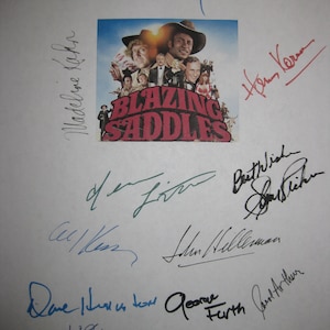 Op de afbeelding: Een witte pagina met een filmposter voor "Blazing Saddles", omringd door meerdere handtekeningen in verschillende kleuren. De poster toont een groep acteurs in een westernsetting.