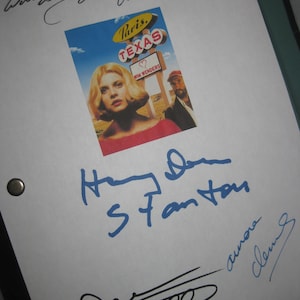 Pode incluir: Um cartão branco com um cartaz de filme azul e amarelo para o filme "Paris, Texas" de Wim Wenders. O cartão é assinado por Harry Dean Stanton, com o texto "With love, Christopher", e uma segunda assinatura em tinta azul.