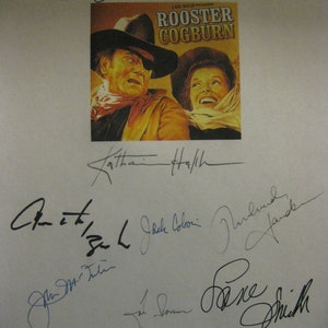 Könnte beinhalten: Ein Schwarzweißfoto eines Filmplakats für den Film "Rooster Cogburn" mit Unterschriften der Besetzung und Crew, darunter John Wayne, Katherine Helmond und Strother Martin.