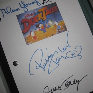 May include: A white page with three signatures. The top signature is in blue ink and says "Alan Young." The middle signature is in blue ink and says "Russi Taylor." The bottom signature is in black ink and says "Jene  Barclay." The page also features a colour image of the Disney DuckTales cartoon characters.