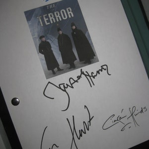 May include: A white sheet of paper with three signatures. The signatures are "Denis Menace", "Dan Aykroyd" and "Ciara Hinds". The paper also has the title "THE TERROR" printed on it.