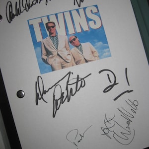 Może przedstawiać: Biały scenariusz z czarnymi podpisami członków obsady filmu "Bliźniacy". Podpisy należą do Arnolda Schwarzeneggera, Danny'ego DeVito, Kelly Preston i czwartej osoby, której podpis jest nieczytelny. Scenariusz zawiera zdjęcie dwóch aktorów z filmu z tytułem "Bliźniacy" nad nimi.